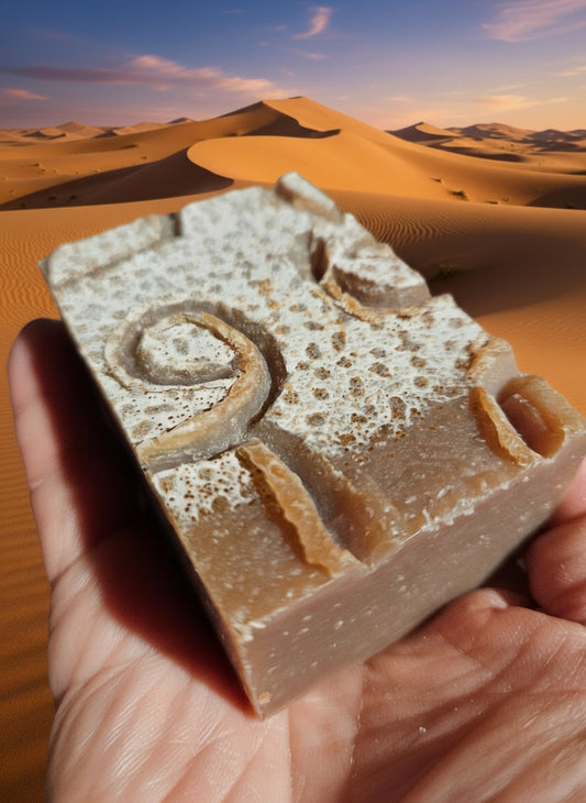 Bar of soap with a decorative design held in front of sand dunes