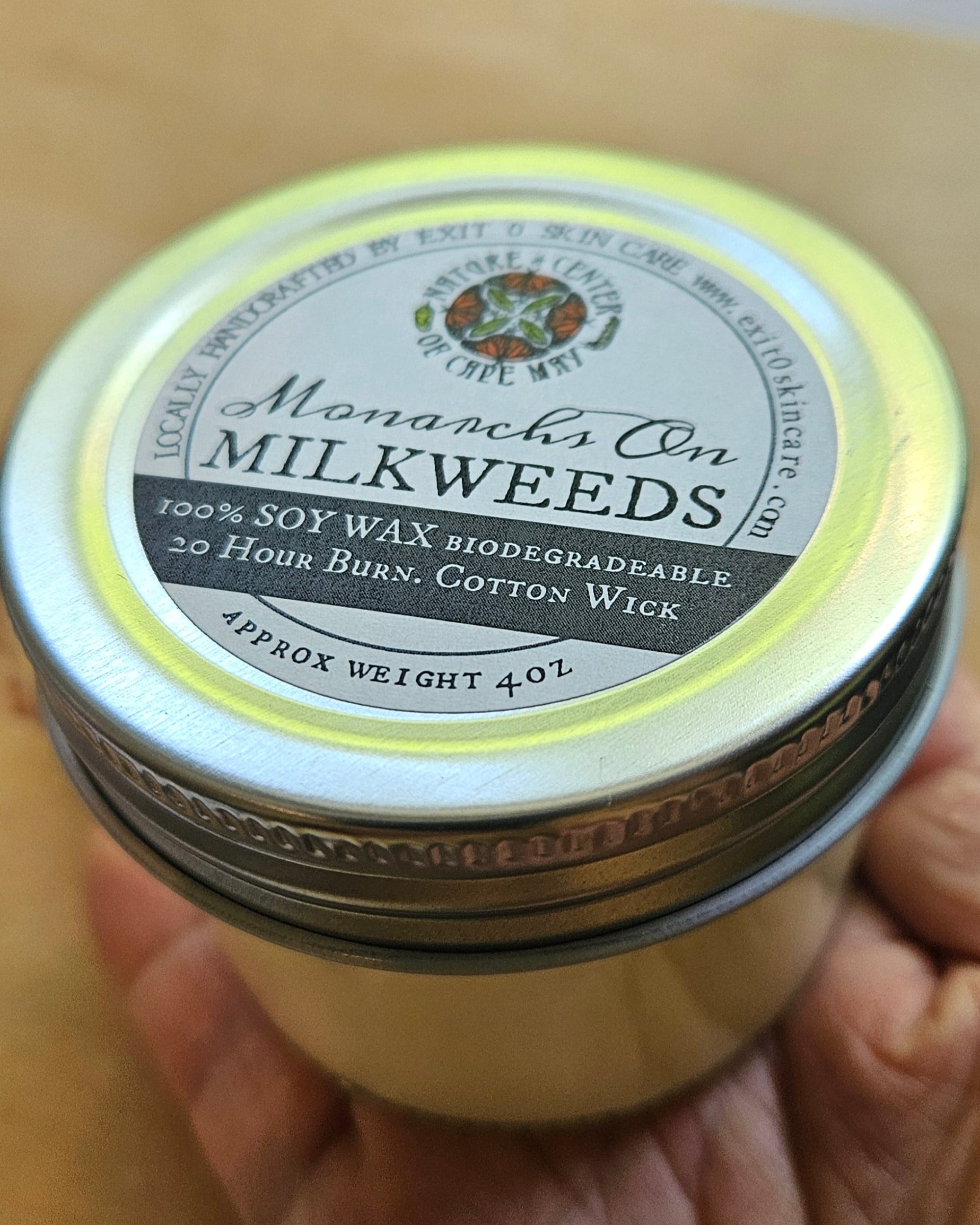 Hand holding a jar of Alpena's Milkweeds Honey with a blurred background