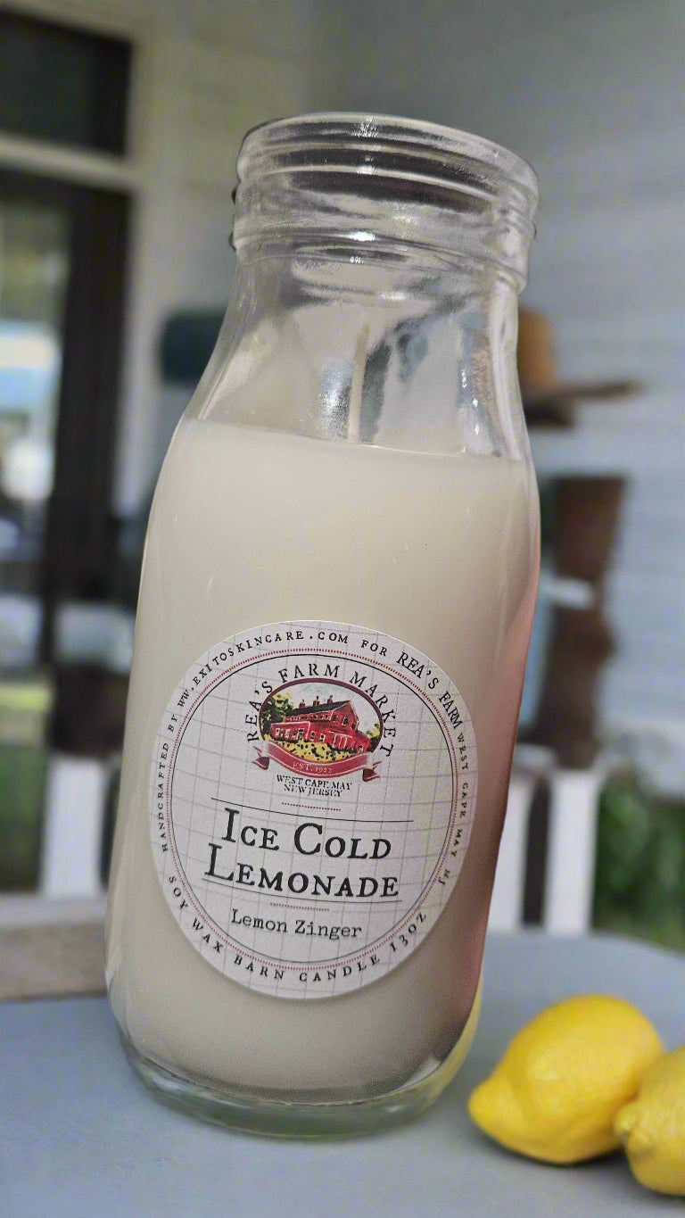 Glass bottle of ice cold lemonade with a label on a table outdoors.