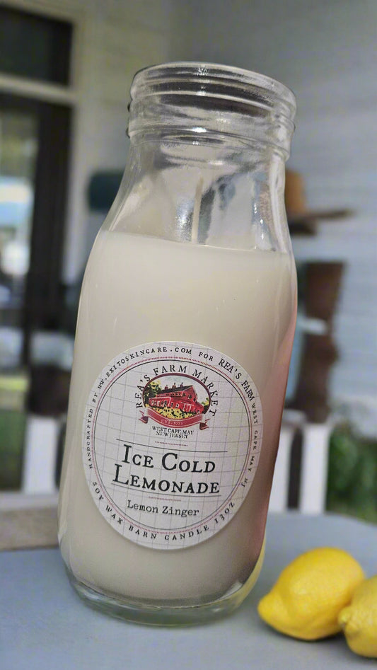 Glass bottle of ice cold lemonade with a label on a table outdoors.