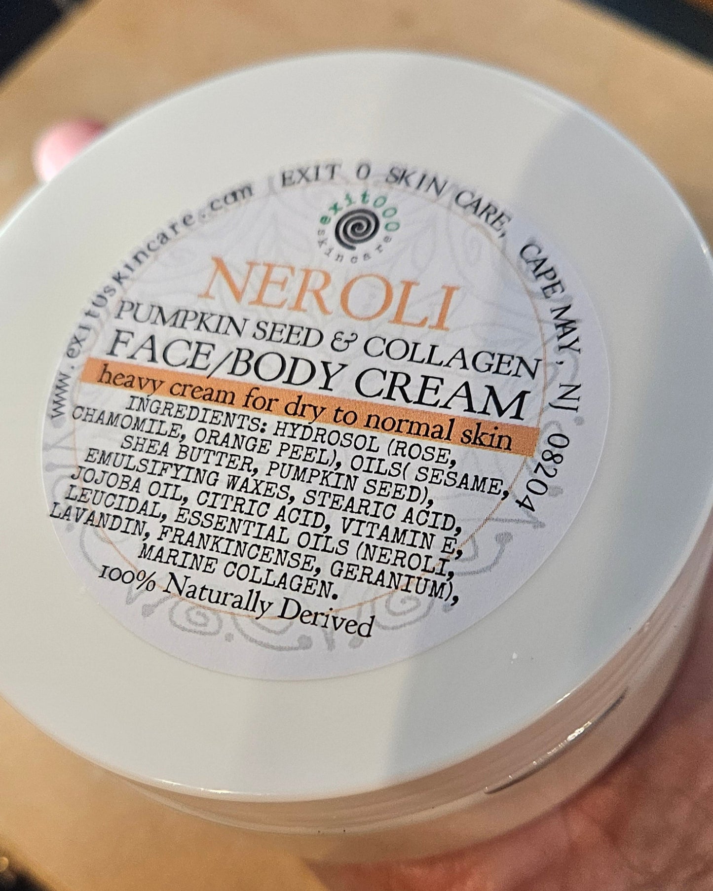 Jar of NEROLI pumpkin seed & collagen face and body cream on a wooden surface