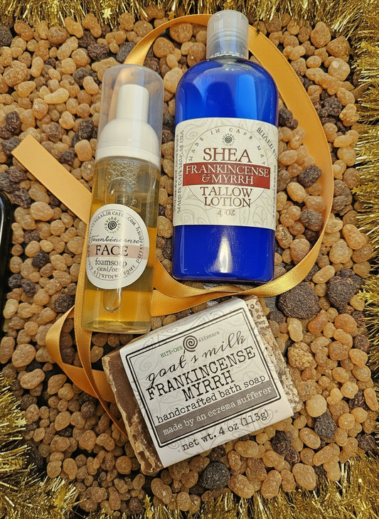 Two bottles and a bar of soap on a dark surface with a yellow ribbon.