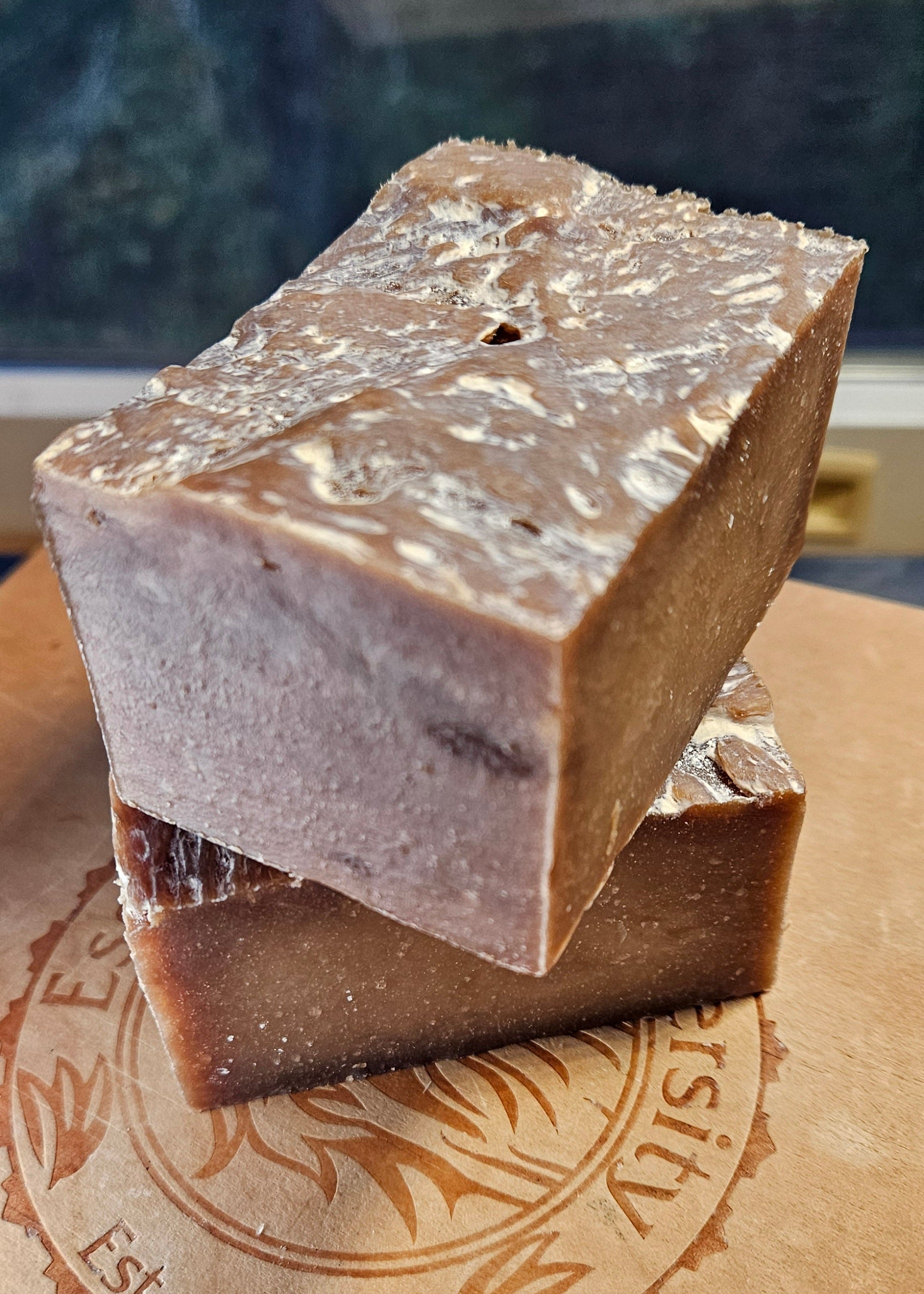 Two soap bars on a brown surface with a logo in the background