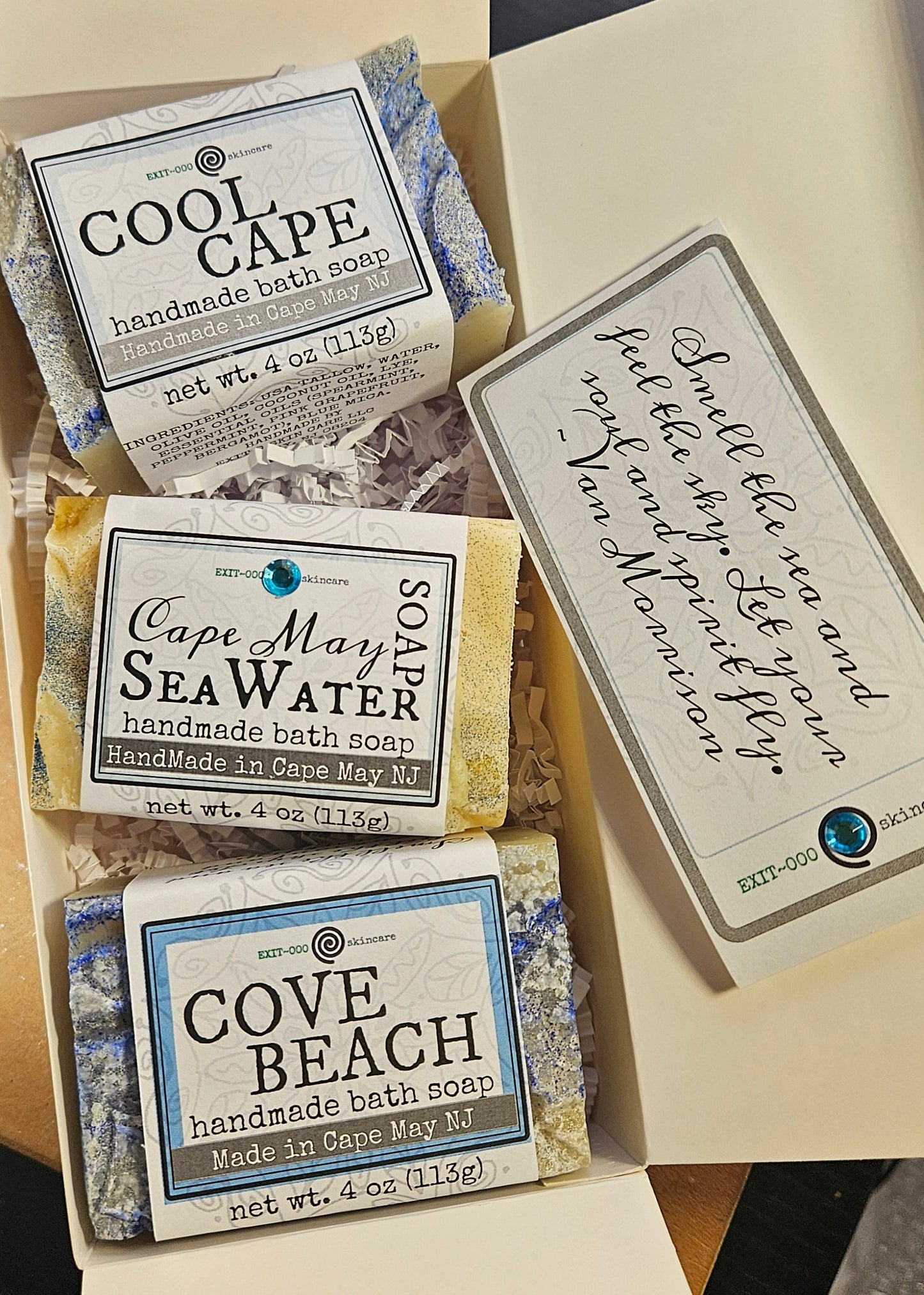Box of soap bars with 'Cape May' and 'Cove Beach' branding on a wooden surface.