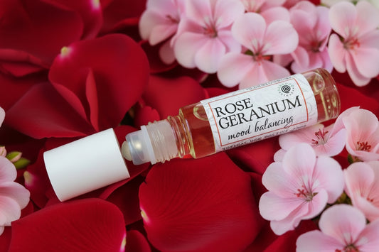 Roll-on bottle of Rose Geranium essential oil on a wooden surface with a brand logo.