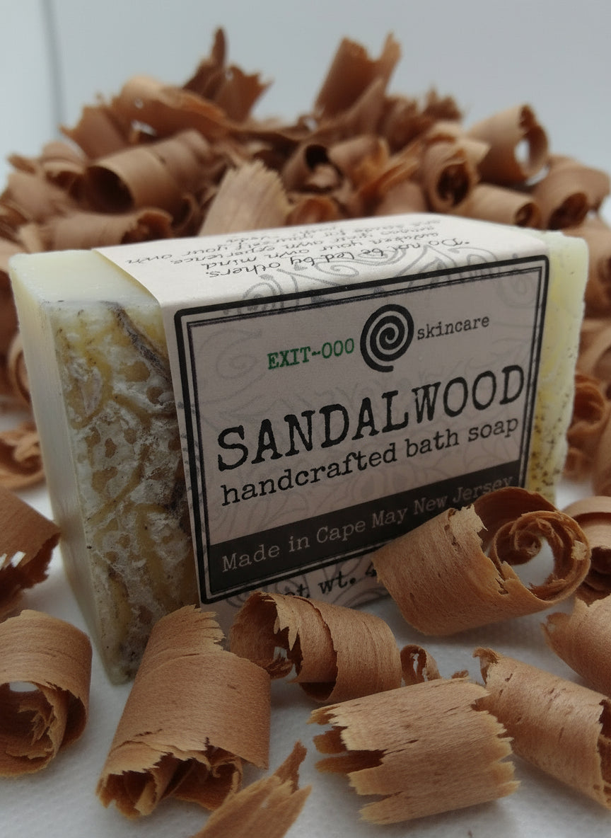 A packaged bar of Sandalwood handcrafted bath soap with visible natural patterns on the surface, labeled as made by an artisan craftsman.