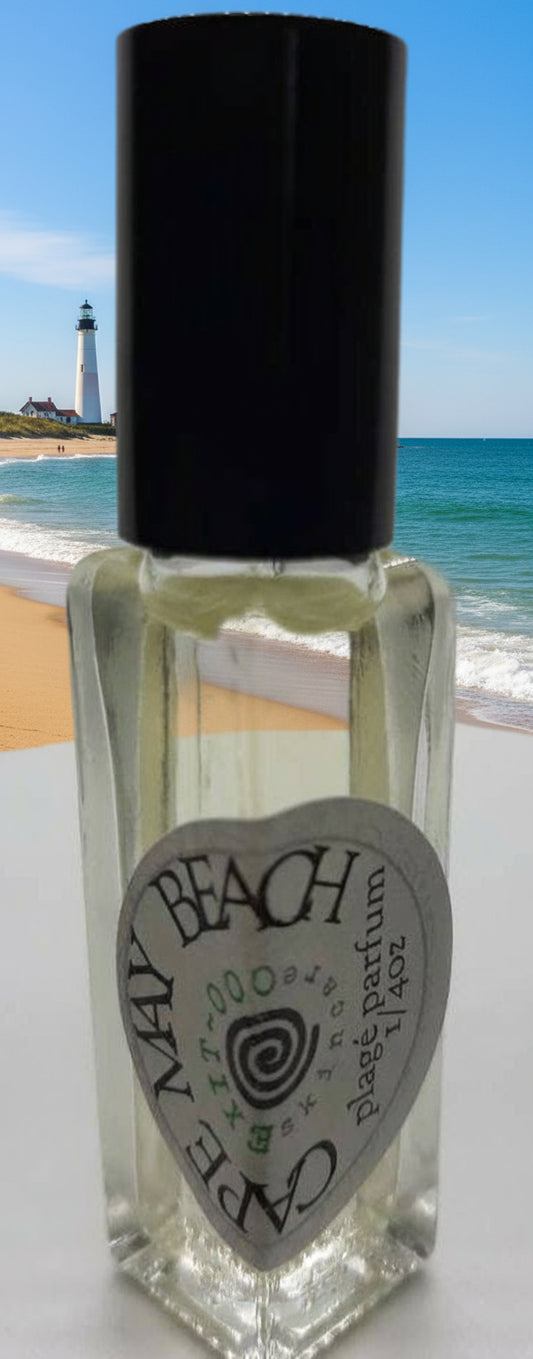 A small, clear glass bottle with a black cap, labeled 'CAPE MAY BEACH'. The bottle contains a clear liquid, presumably the natural parfum.