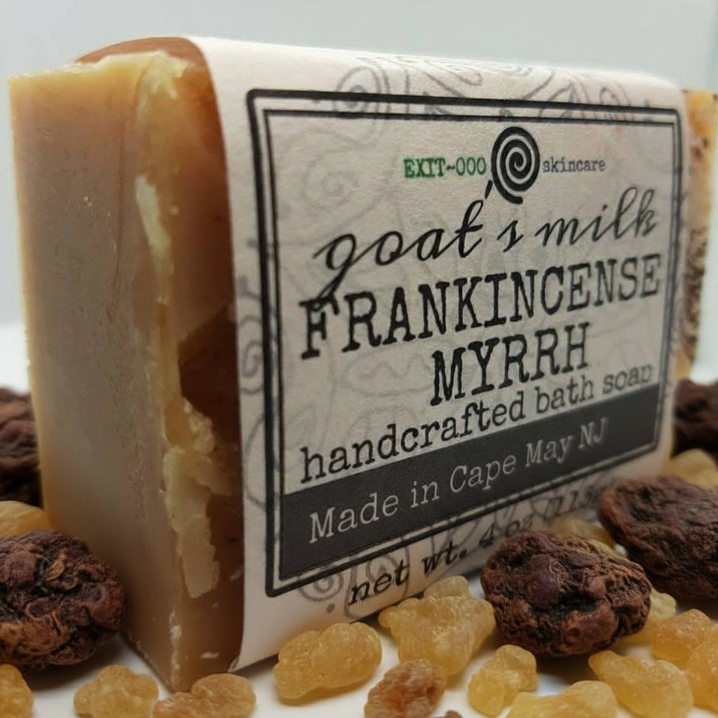 A bar of goat's milk soap labeled 'Frankincense Myrrh' with a beige color and textured surface.