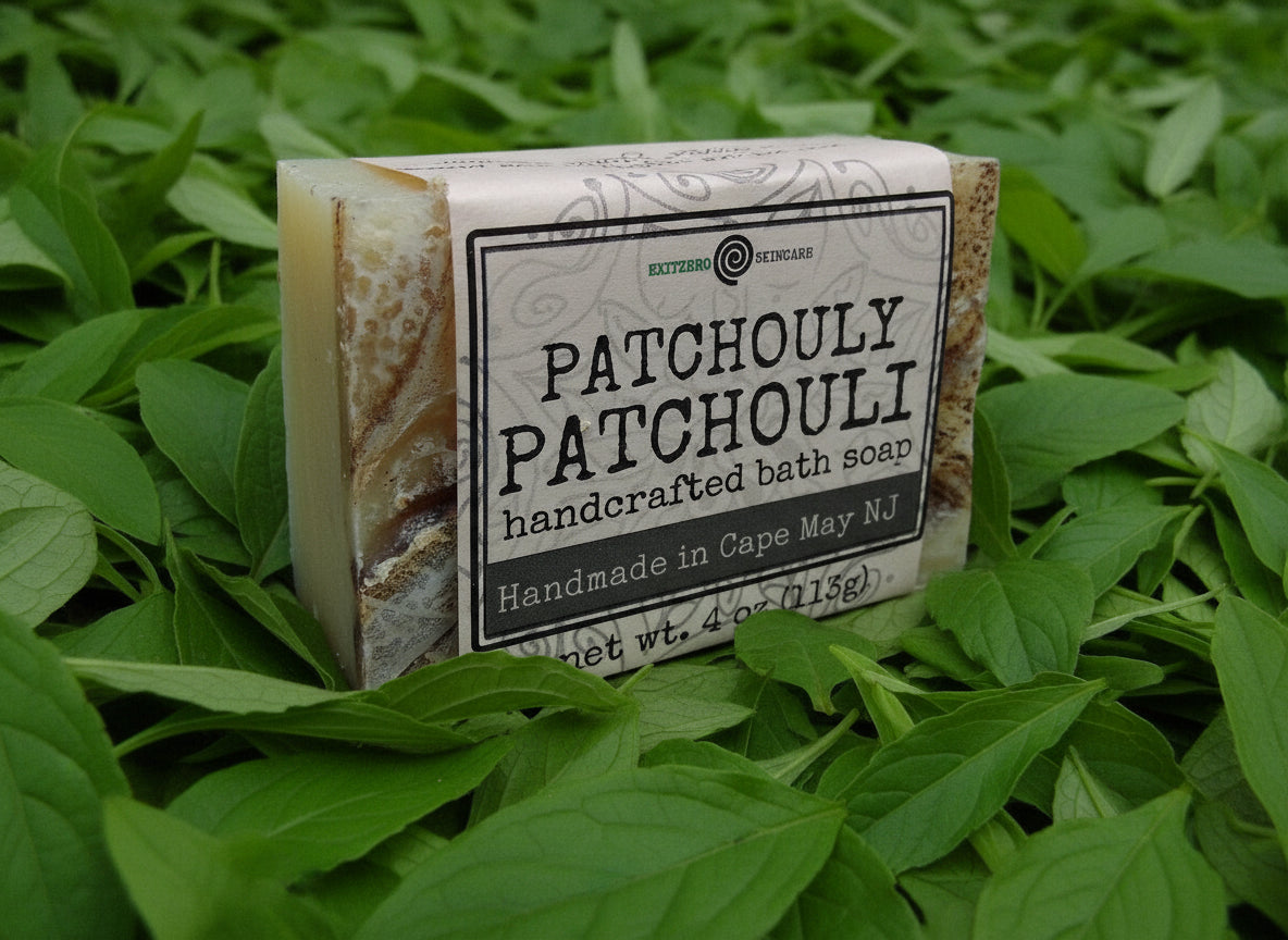 A bar of soap with a beige base and brown edges, featuring a label that reads 'PATCHOULI PATCHOULI handcrafted bath soap made by an essential soaps', indicating it is a Patchouli-scented product.